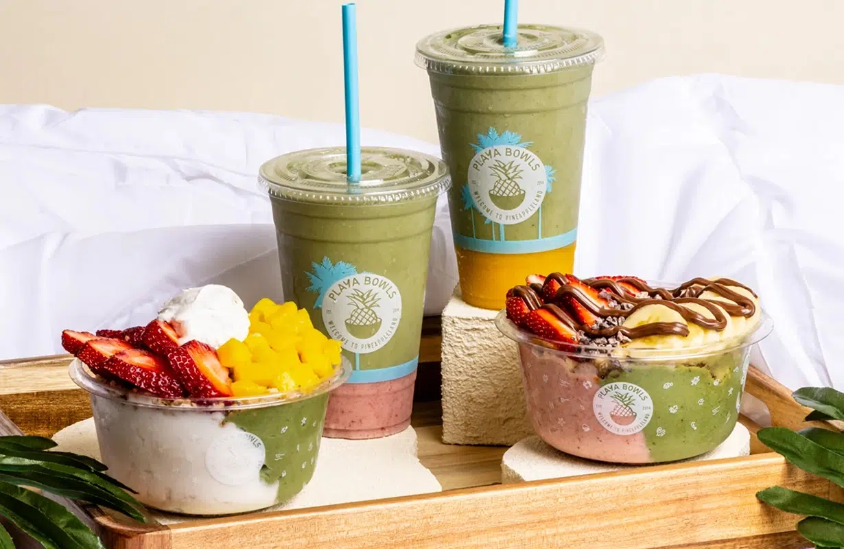a tray of smoothies and bowls with fruit and whipped cream