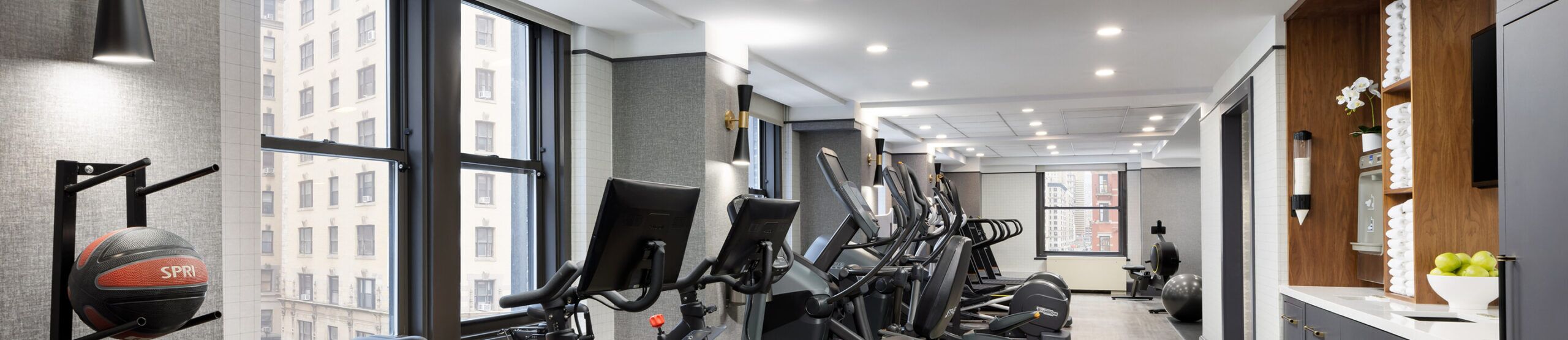a gym with treadmills, exercise balls, and a TV