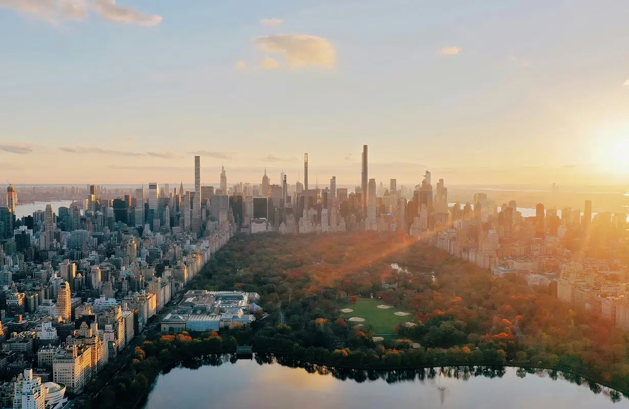 Aerial view of a city skyline at sunset with a large park in the foreground.