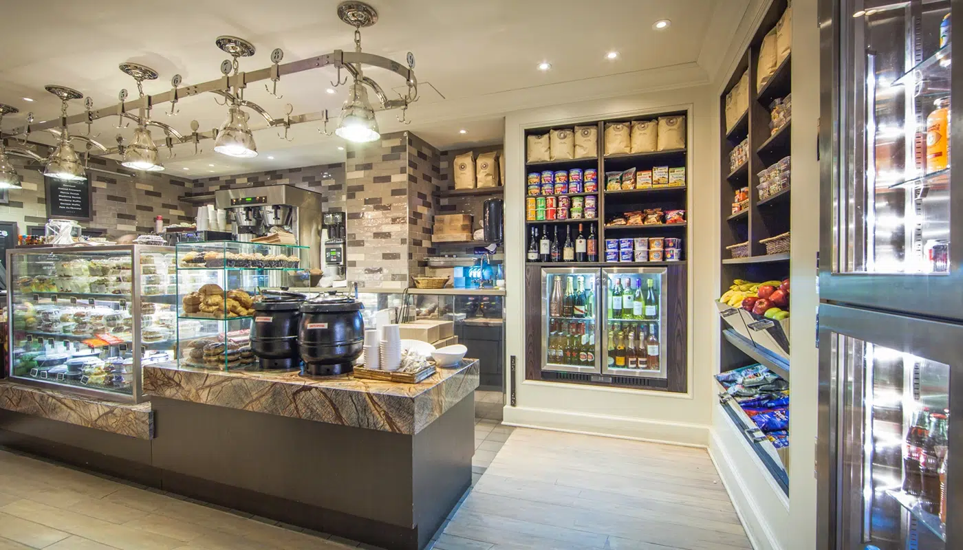 A convenience store in a hotel lobby with a marble countertop, glass display cases, and refrigerators stocked with various products.