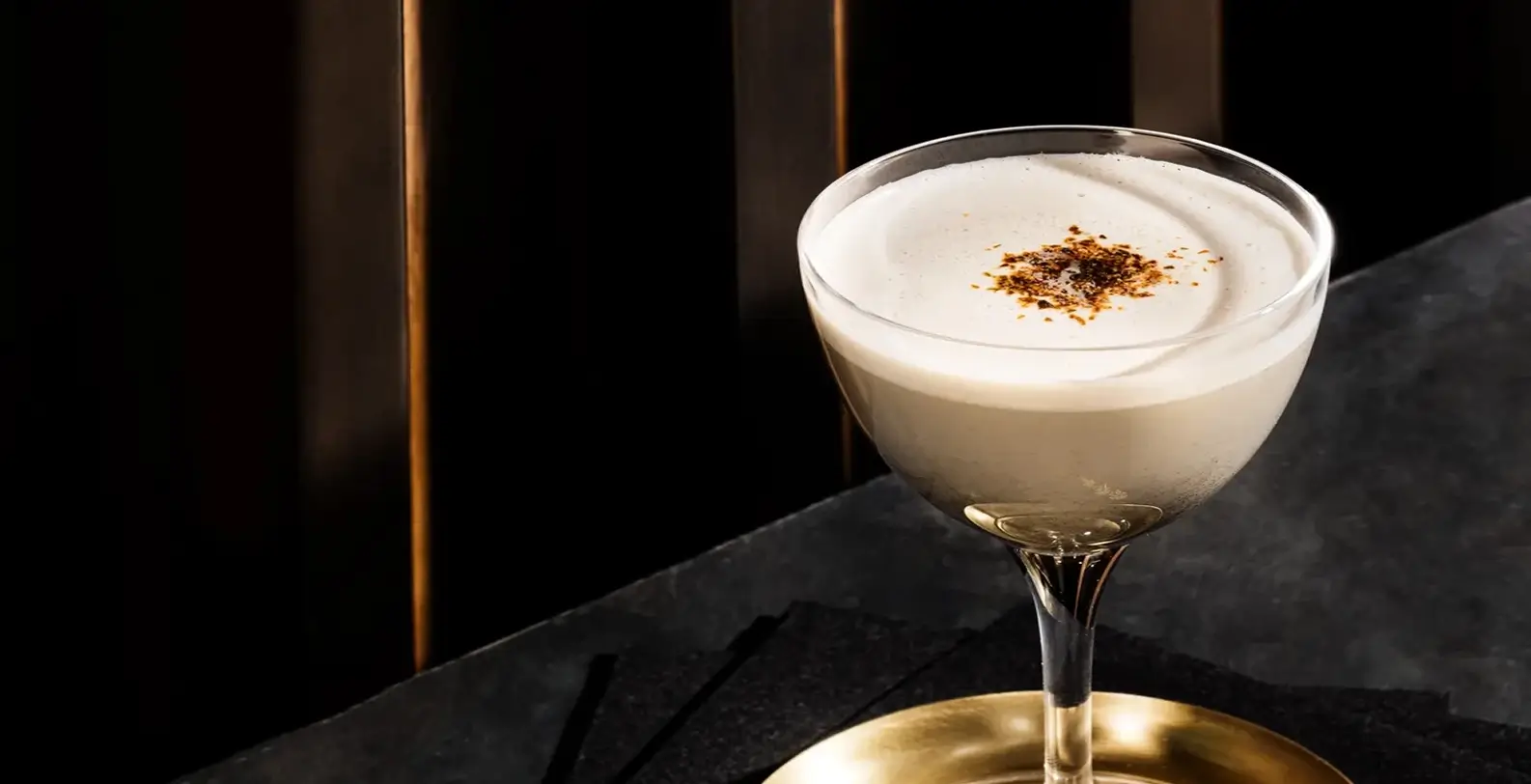 a creamy cocktail in a stemmed glass on a table