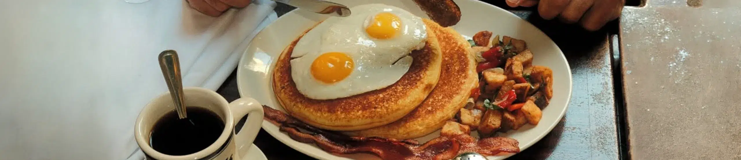 a plate of pancakes with eggs, bacon, and hash browns
