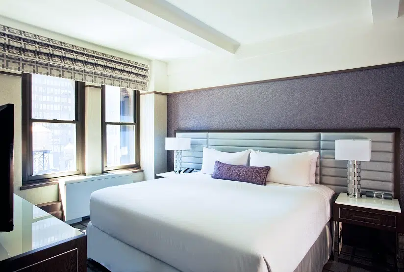 A Premier King Room with a large bed, window, flat-screen TV, and modern furnishings.